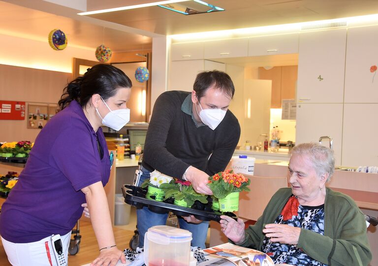 Eine Bewohnerin wird vom Führungs-Duo mit Blumen bedacht.