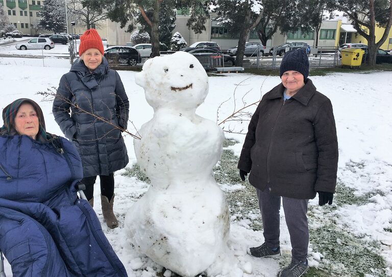 Drei Bewohnerinnen mit dem fertigen Schneemann im Garten.