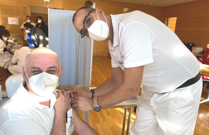 Ein Arzt impft einen Kollegen.