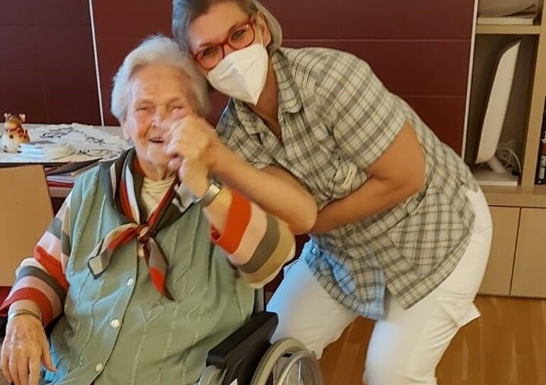 Mitarbeiterin Petra tanzt mit einer Bewohnerin.