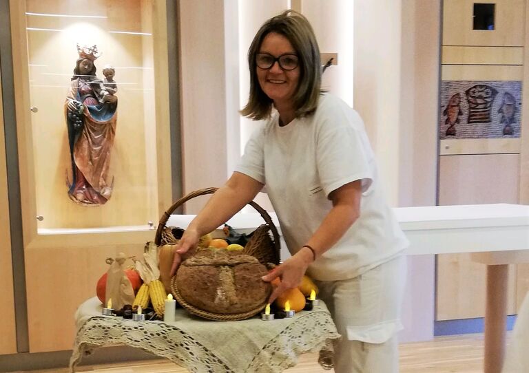 Ankica, Mitarbeiterin im HB Am Maurer Berg St. Josef, mit der Erntedank Dekoration und selbst gebackenem Brot.