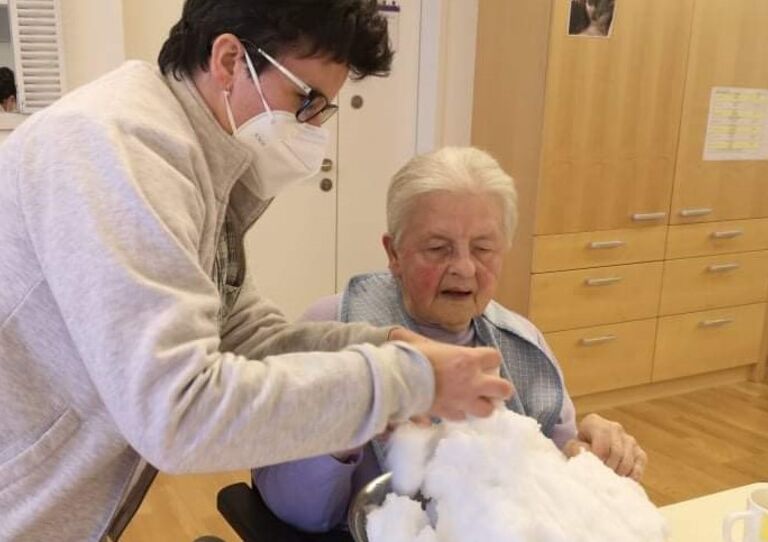 Mitarbeiterin Romana formt mit einer Bewohnerin Schneebälle.