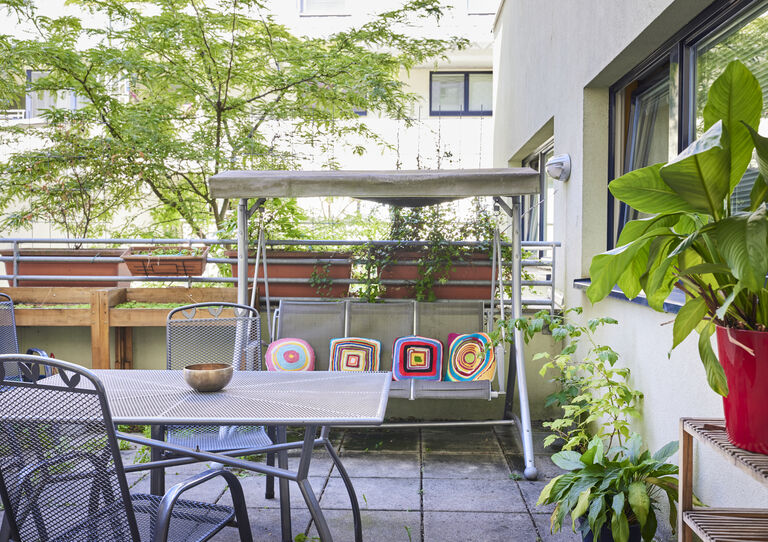Terrasse der WG Schanzstraße mit Hollywood-Schaukel und Gartenmöbeln und einem Baum im Hintergrund