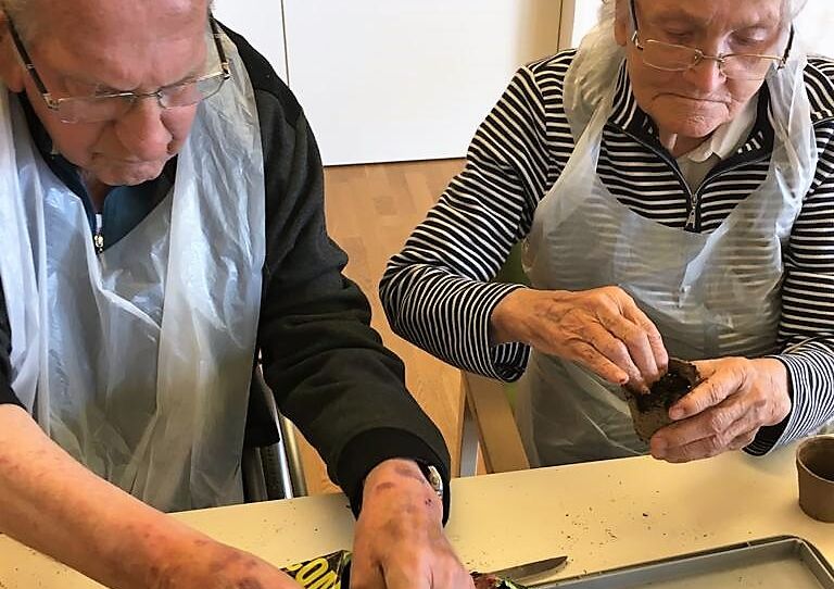 Zwei Bewohner füllen Töpfe mit Erde