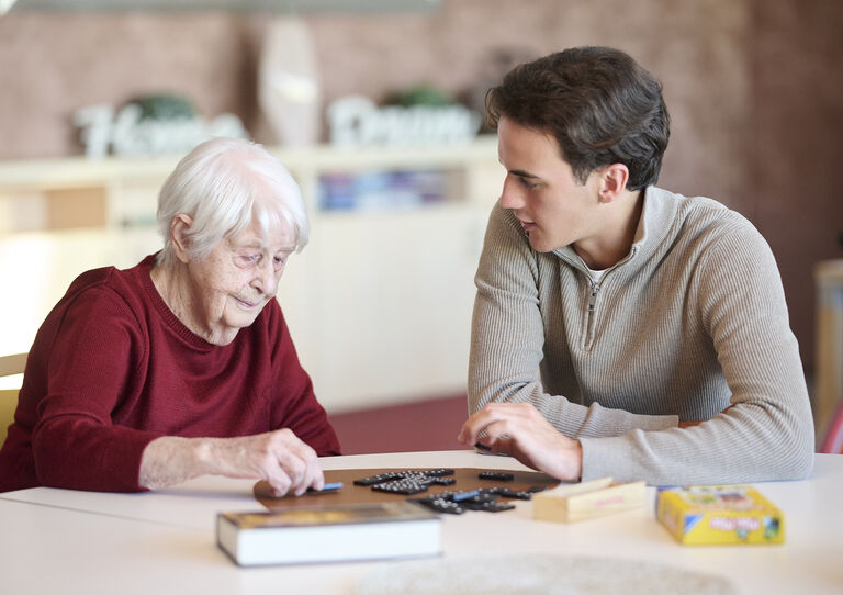 Ein Student spielt Domino mit einer Bewohnerin. Ein Student spielt Domino mit einer Bewohnerin.