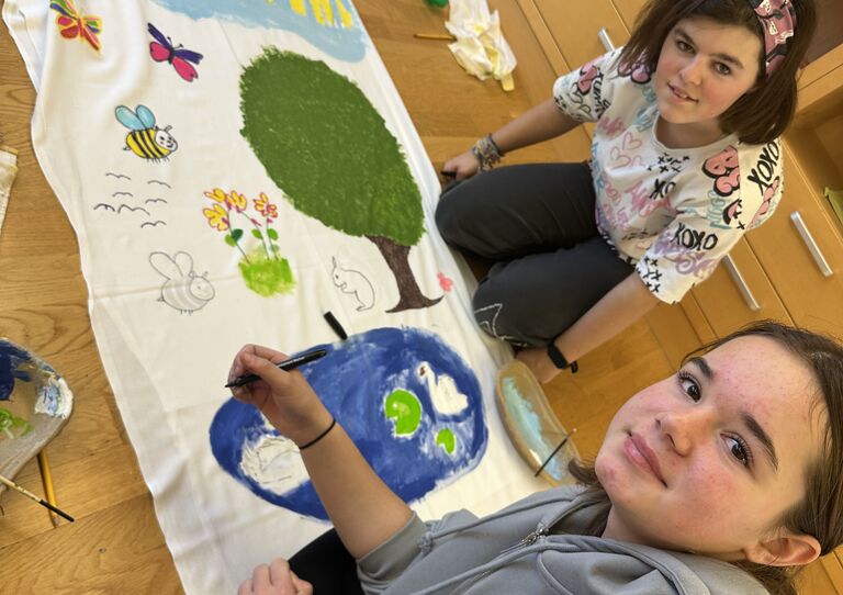 Unsere Praktikantinnen Lina und Elisabeth bemalten ein Leinentuch für bettlägerige Bewohner*innen