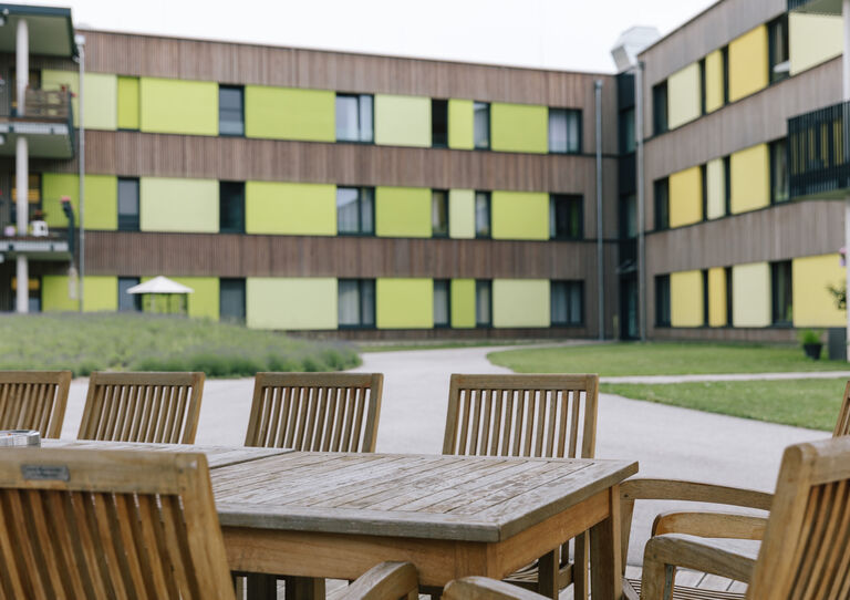 Eine Terasse im Innenhof des Stephansheims mit Holzstühlen und einem Holztisch.