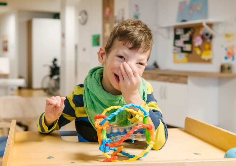Kleiner Bub, der sich ins Gesicht greift.