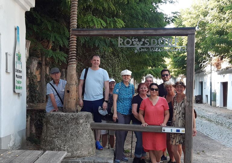 Mitarbeiter*innen Urbanusheim posieren für ein Gruppenbild in einem Lebensechten Bilderrahmen, der in Poysdorf steht.