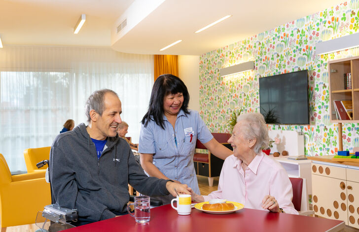 Mitarbeiterin und Bewohner*innen im Wohnbereich.