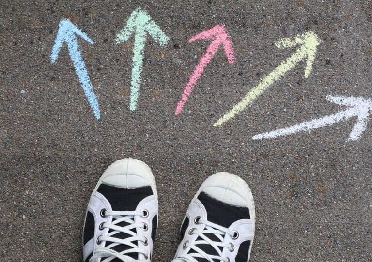 Turnschuhe mit Pfeilen aus Kreide die auf den Boden gezeichnet sind. 
