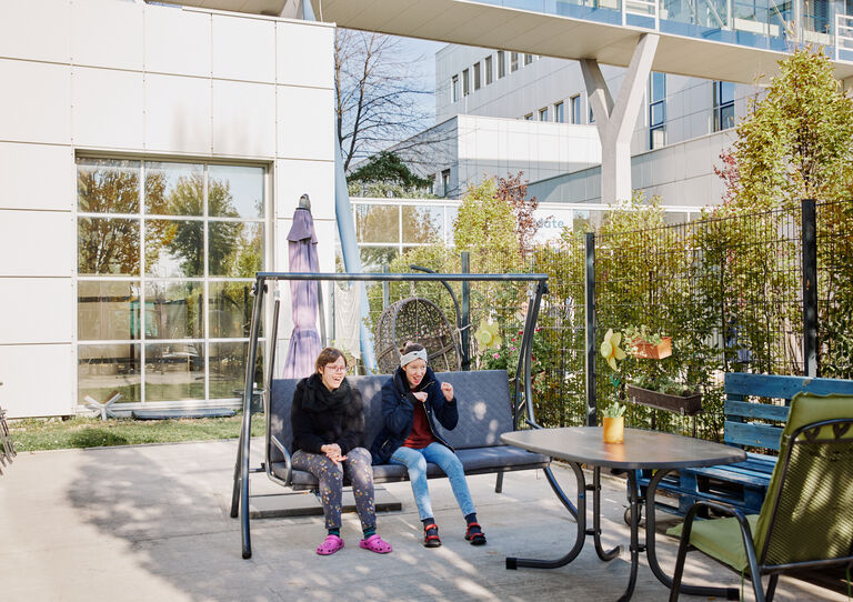 BTZ Maria-Rekker-Gasse: Garten: Zwei Kundinnen schaukeln auf der Hollywood-Schaukel. 