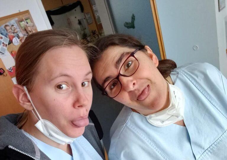 Zwei Kolleginnen lachen miteinander, eine streckt die Zunge raus.