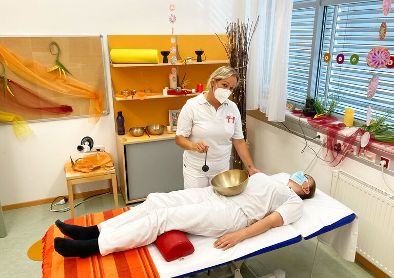 Eine HB-Mitarbeiterin gibt einer Kollegin eine wohltuende Klangschalenmassage.