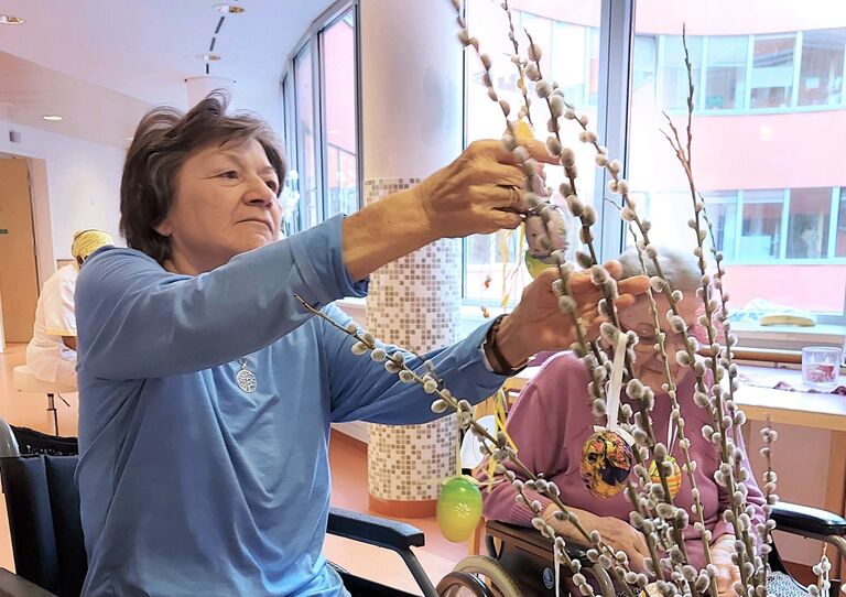 Eine Bewohnerin schmückt den Osterstrauch.