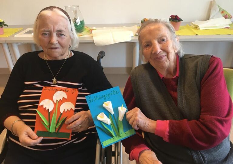 Bewohnerinnen zeigen ihre selbst gebastelten Frühlingskarten her.