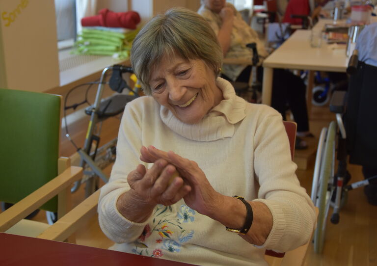 Eine Bewohnerin lacht und klatscht in die Hände.