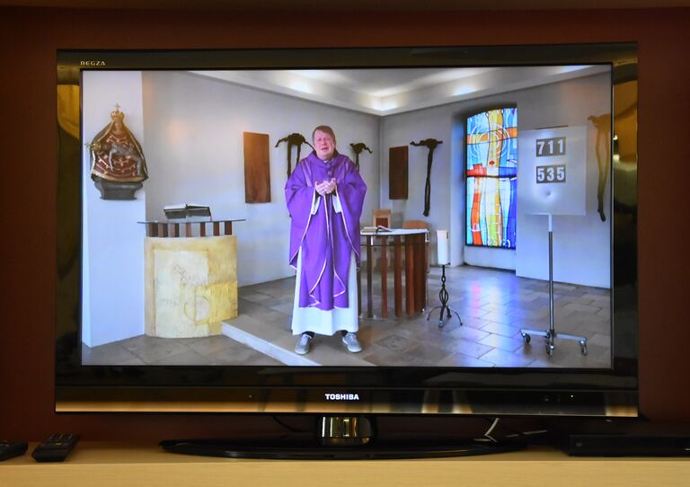 Fernsehbildschirm, auf dem die Übertragung der Messe zu sehen ist.