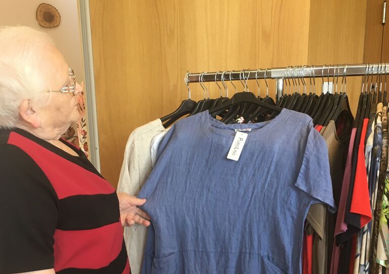 Bewohnerin sieht sich ein blaues Kleid an.