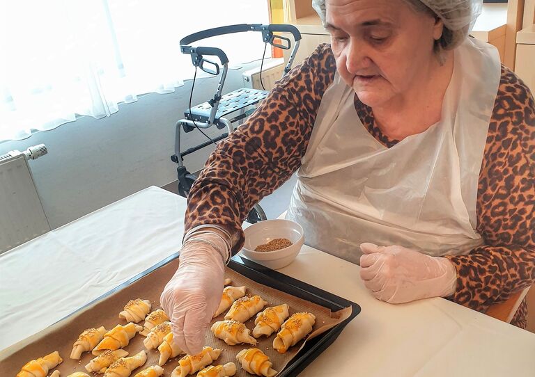 Eine Bewohnerin platziert die Kipferl auf dem Blech.