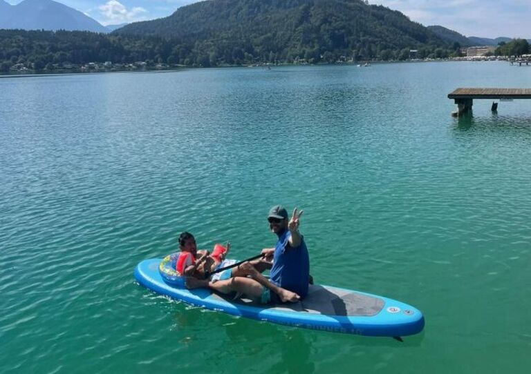Ein Kunde und ein Mitarbeiter sitzen bzw. liegen auf einem Standup Paddle