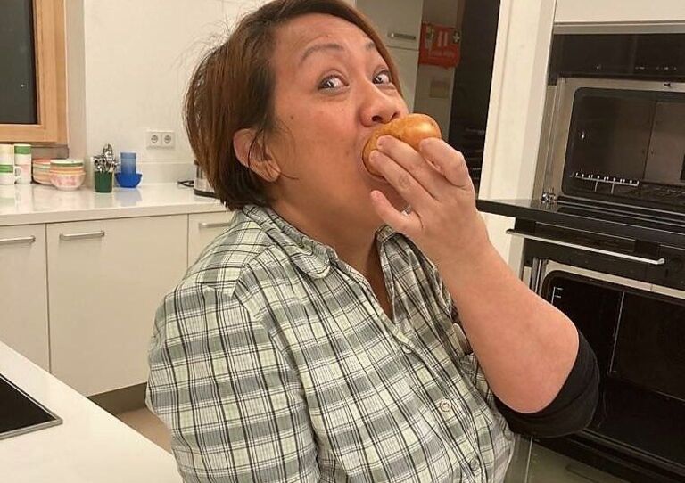 Eine Mitarbeiterin beißt genüsslich in einen Krapfen.