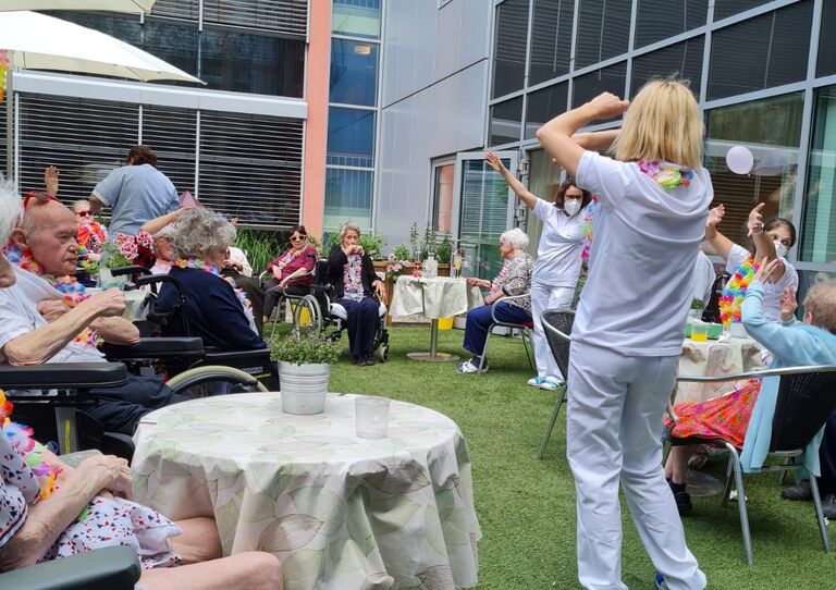 Mitarbeiter*innen tanzen mit Bewohner*innen