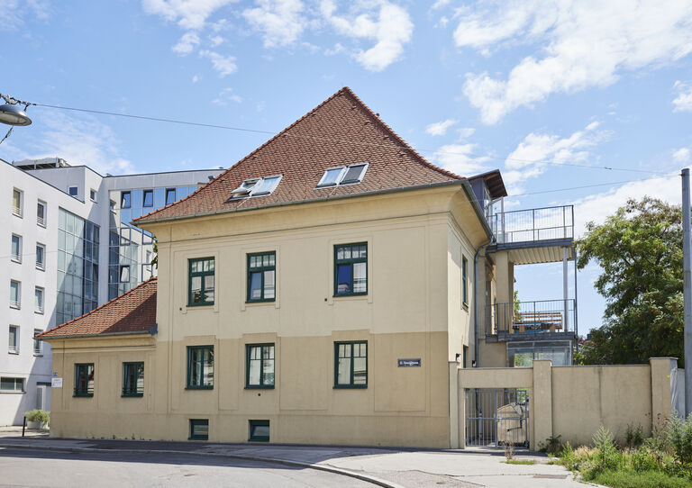 Außenansicht der HABIT WG Oswaldgasse, ein gelbes dreistöckiges Haus mit 2 Balkonen