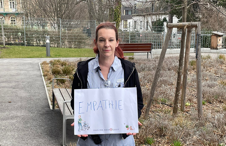 Mitarbeiterin hält Schild mit "Empathie"