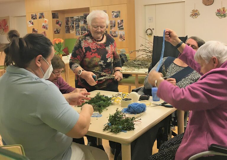 Bewohnerinnen basteln mit Mitarbeiterin Maria Palmbuschen.
