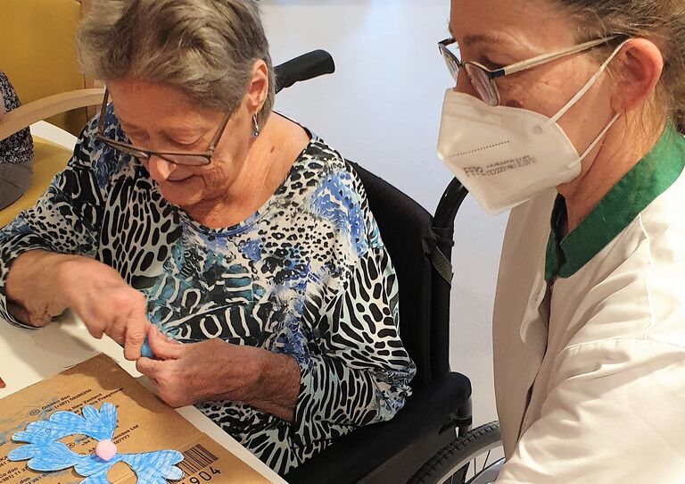 Eine Bewohnerin bastelt mit einer Mitarbeiterin Faschingsdekoration.