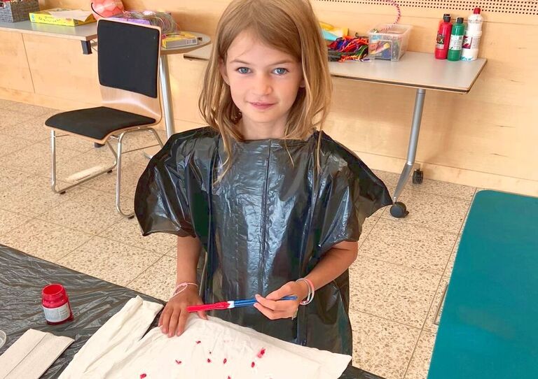 Ein Mädchen bemalt ein T-Shirt mit Kleiderfarben.