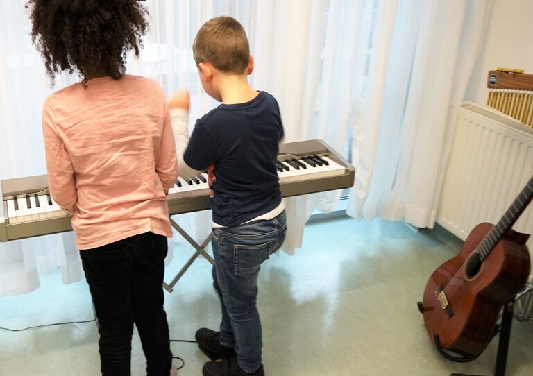 Zwei Kinder spielen auf einem Keyboard.
