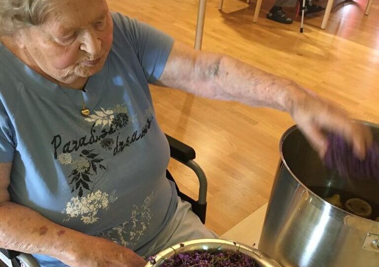 Bewohnerin gibt Lavendel in einen großen Topf zum Einkochen.