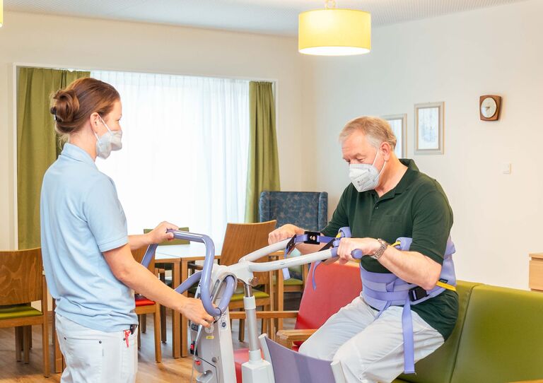 Landesrat Martin Eichtinger bei einem Hilfgerät/Aufstehhilfe, die er von einer Mitarbeiterin erklärt bekommt.