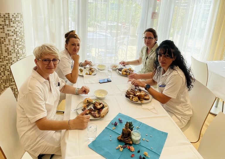 Vier Kolleginnen sitzen am Esstisch und blicken freundlich in die Kamera.