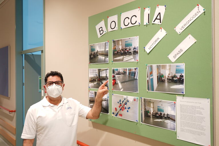 Birkent Zeynel zeigt zu einer Wand, wo einiges über die Therapeutische Wirkung von verschiedenen Gruppenspielen wie Boccia zusammengetragen wurde.