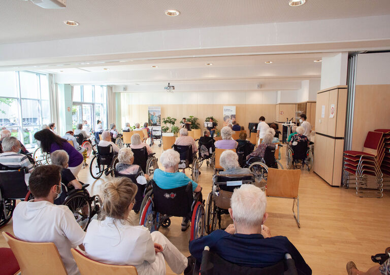 Bewohner*innen und Besucher*innen lauschen dem Konzert.