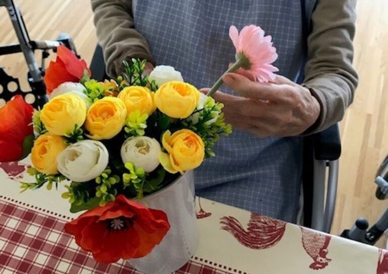 Die Hände einer Bewohnerin, die liebevoll Blumen arrangiert.