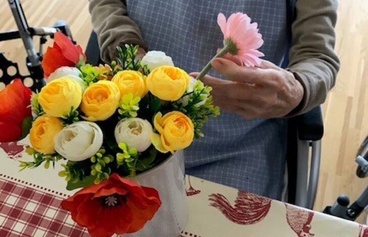 Hände, die Blumen in einer Vase ordnen