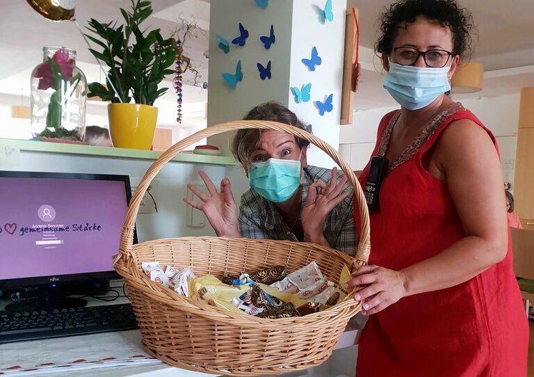 Zwei MitarbeiterInnen mit Geschenkskorb.