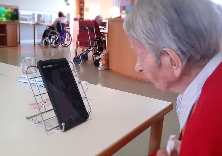 Eine Bewohnerin unterhält sich via Tablet mit Angehörigen.