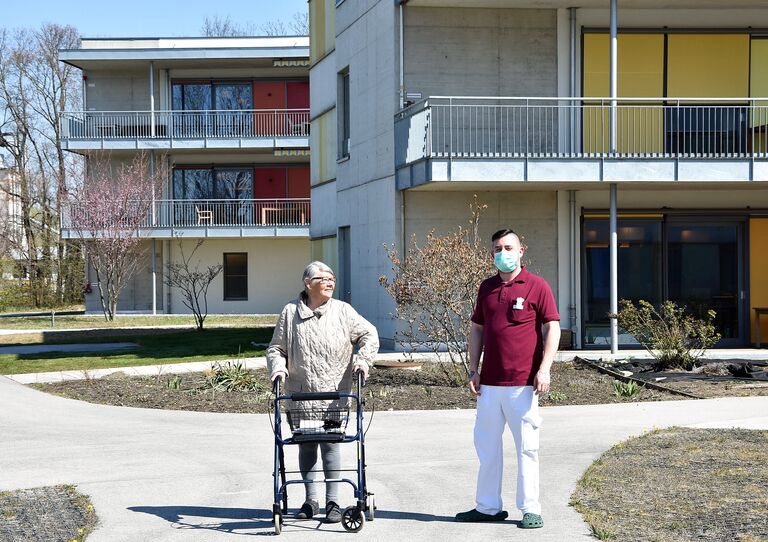Bewohnerin und Pfleger genießen die Sonne im Hof