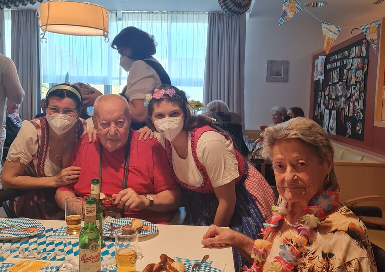 Bewohner*innen und Miarbeiter*innen stecken ihre Köpfe für ein Bild zusammen und lächeln in die Kamera.