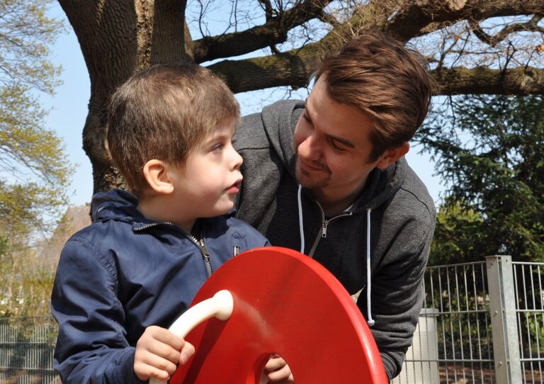 Betreuer mit Kind am Spielplatz.