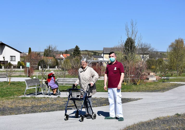 Bewohnerin und Pfleger genießen die Sonne im Hof