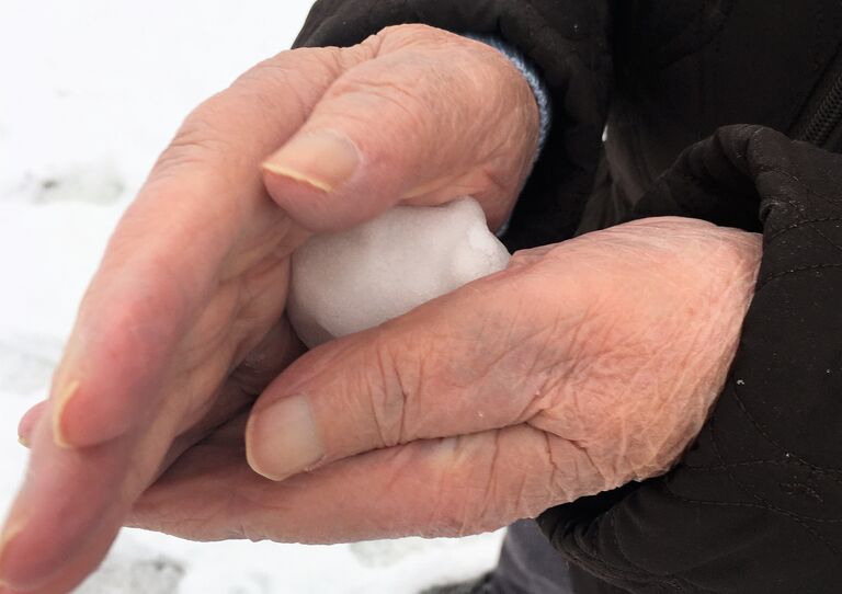 Die Hände einer Bewohnerin formen Schneebälle.