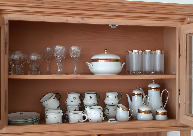 Eine Geschirrvitrine aus Holz und Glas mit elegantem Porzellangeschirr.