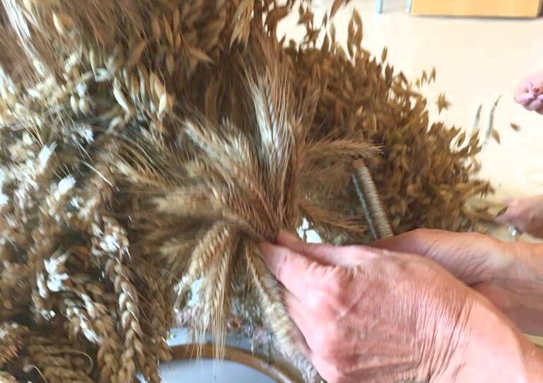 Man sieht die Hand einer Bewohenrin, die eine Erntedankkrone bastelt.