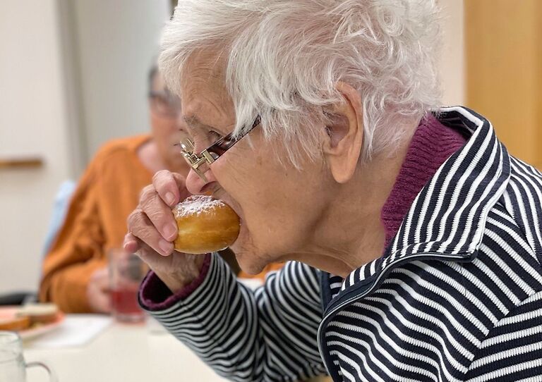 Eine Bewohnerin probiert einen frischen Krapfen.